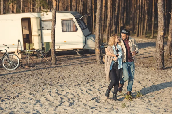 Young couple with glasses of wine walking near campervan — Stock Photo