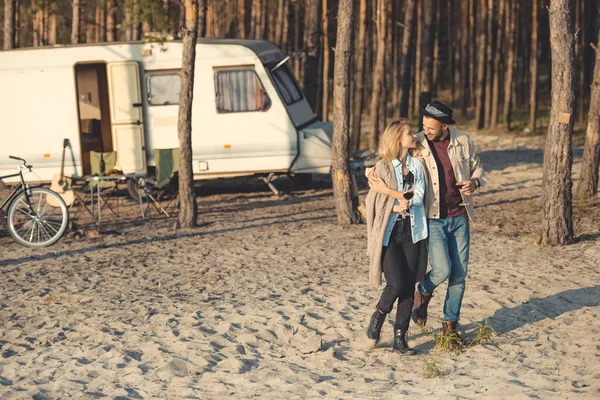 Pareja joven con copas de vino caminando cerca campervan - foto de stock