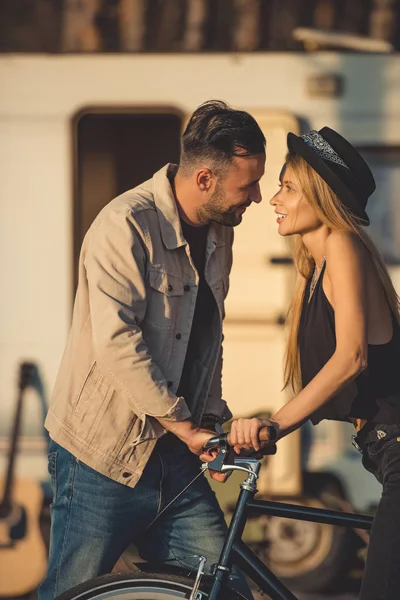 Красива щаслива пара дивиться один на одного, стоячи разом з велосипедом біля трейлера — стокове фото