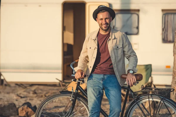 Glücklich schöner Mann lehnt auf Fahrrad in der Nähe Anhänger — Stockfoto