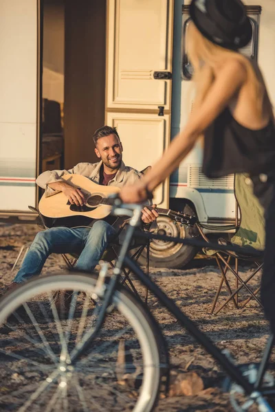 Selective focus of girl with bicycle and man playing guitar near trailer — Stock Photo