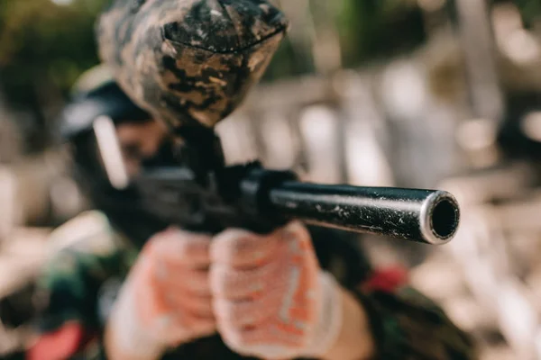 Foco seletivo do jogador de paintball em camuflagem visando a pistola de paintball ao ar livre — Fotografia de Stock