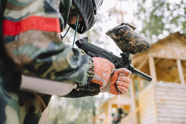 Vue partielle du joueur de paintball masculin en masque de masque et camouflage avec pistolet de paintball à l'extérieur — Photo de stock