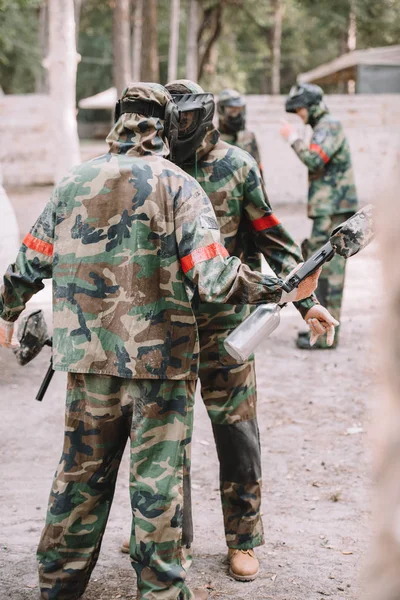 Male paintballers in protective masks and camouflage fighting face to face outdoors — Stock Photo