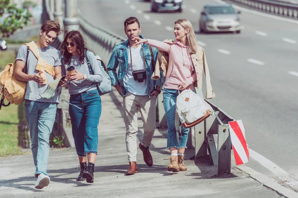 Jóvenes amigos con mapa y mochilas viajando juntos en la nueva ciudad - foto de stock