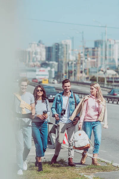 Jóvenes amigos con mapa y mochilas viajando juntos en la nueva ciudad - foto de stock