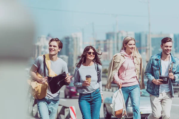 Amigos sonrientes con mapa y mochilas viajando juntos en la nueva ciudad - foto de stock