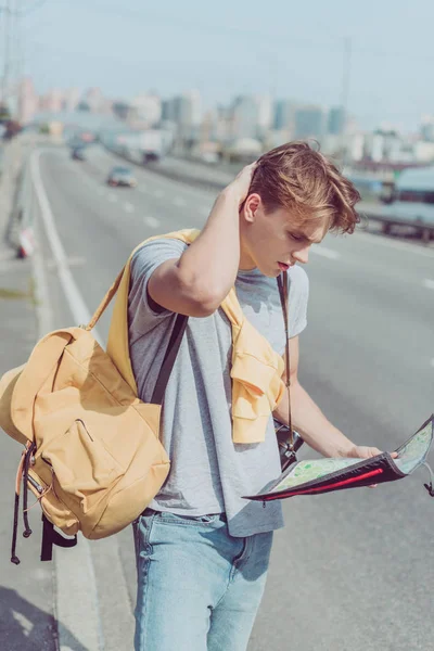 Young man with map and backpack looking for destination — Stock Photo