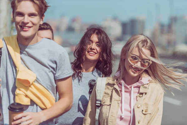 Частичный вид улыбающихся молодых путешественников, идущих по улице, путешествуя вместе — стоковое фото