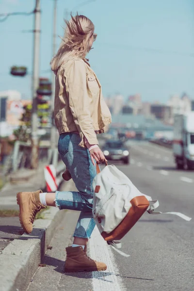 Partial view of female traveler with backpack crossing road in new city — Stock Photo