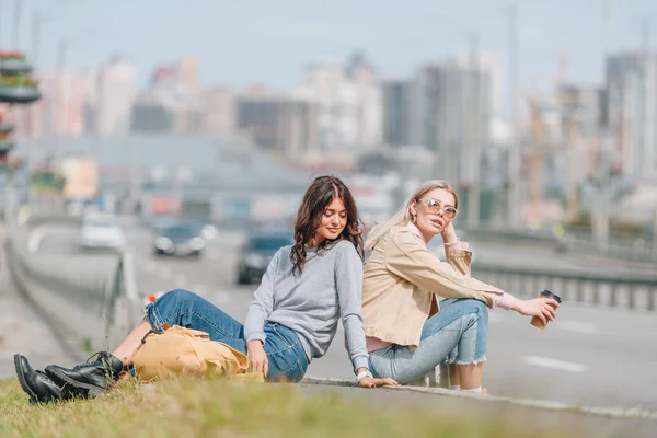 Female travelers resting on green grass during trip in new city — Stock Photo