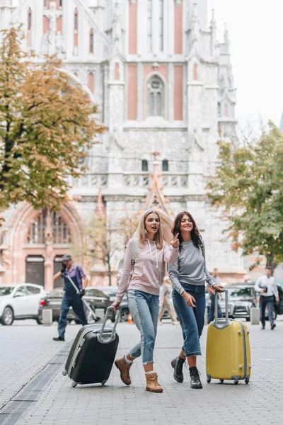 Turistas femeninos con mochilas y equipaje caminando por la calle de la ciudad - foto de stock
