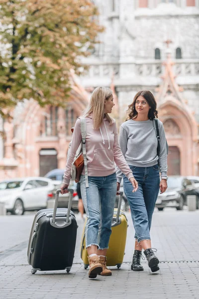 Touristes féminines avec sacs à dos et bagages marchant dans la rue de la ville — Photo de stock