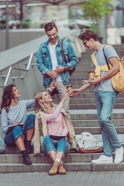 Men brought coffee to go to friends on street steps in new city — Stock Photo