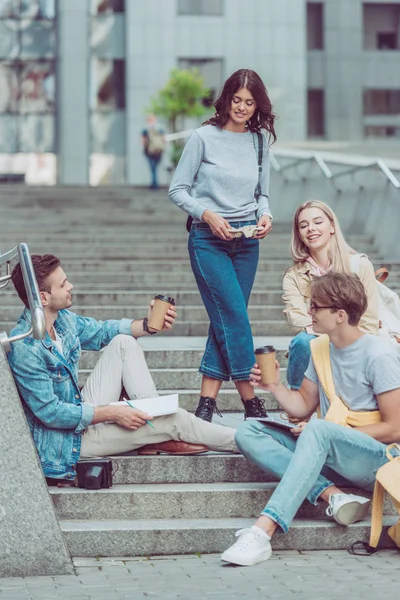 Amici con caffè per andare a riposare sui gradini di strada nella nuova città — Foto stock