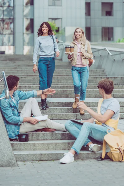 Smiling women brought coffee to go for friends on street steps in new city — Stock Photo