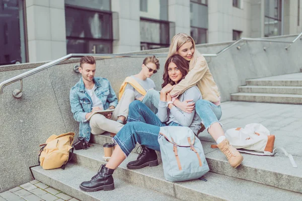 Young tourists resting on steps on street of new city — Stock Photo