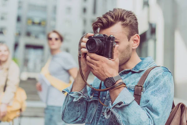 Selective focus of man taking picture on photo camera of new city during journey — Stock Photo