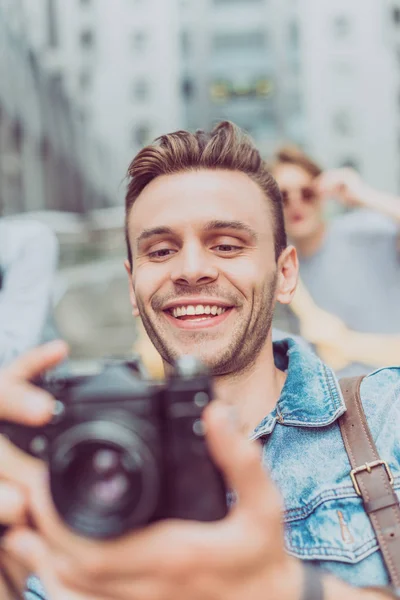 Selective focus of smiling man with photo camera traveling in new city — Stock Photo