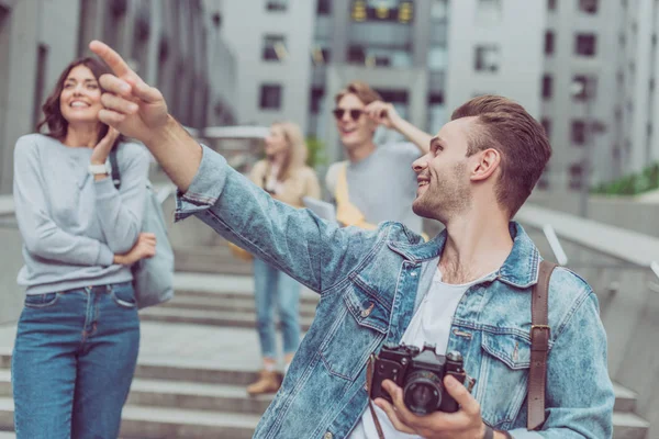 Photographer with camera showing something to friends in city — Stock Photo