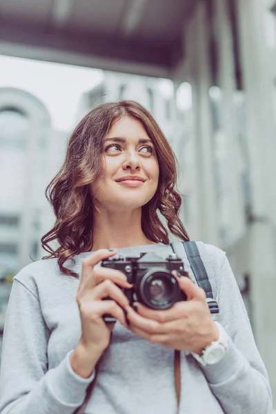 Atractiva mujer morena con cámara de fotos en la ciudad - foto de stock