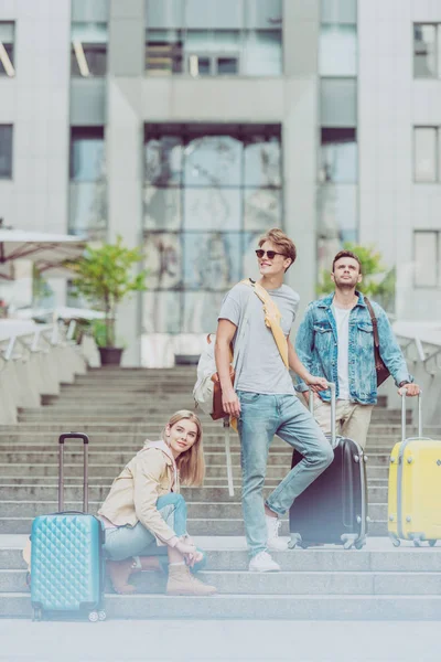 Turistas elegantes con mochilas y maletas de viaje en las escaleras de la ciudad - foto de stock