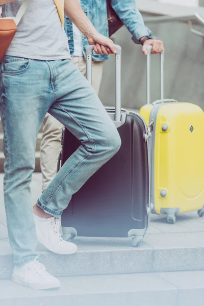 Cropped view of young male tourists with suitcases — Stock Photo