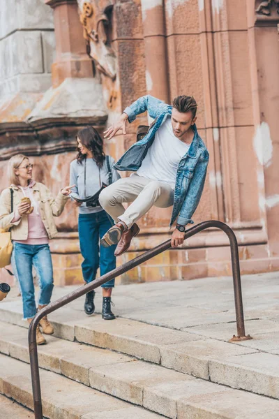 Hermosas chicas pasando tiempo juntos en la ciudad mientras el hombre saltando sobre barandilla - foto de stock