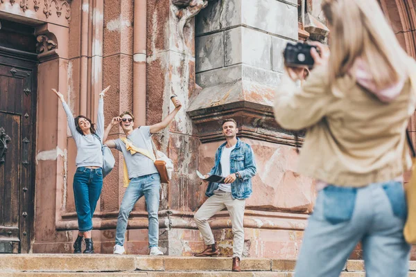 Selective focus of girl taking photo of excited tourists on camera in city — Stock Photo