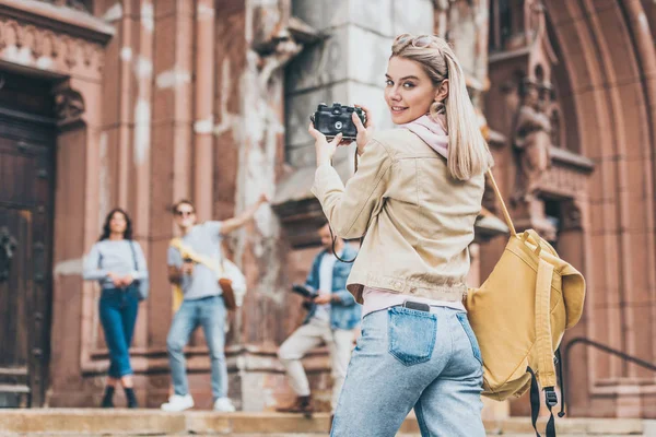 Chica feliz tomando fotos de amigos en la cámara en la ciudad - foto de stock