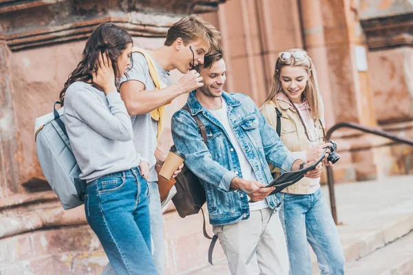 Cheerful tourists looking at map in city — Stock Photo