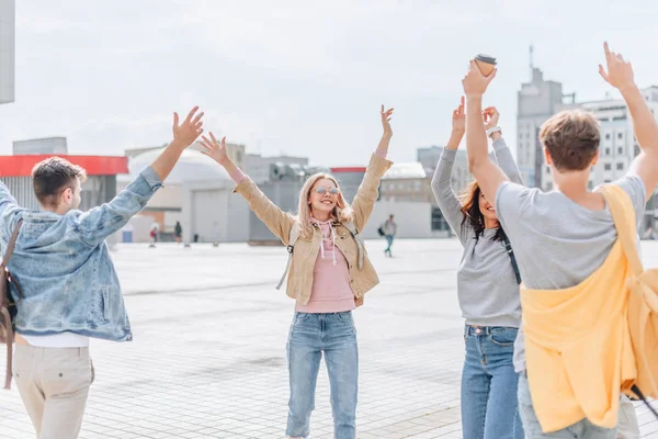 Jóvenes viajeros felices saludando y caminando en la ciudad - foto de stock