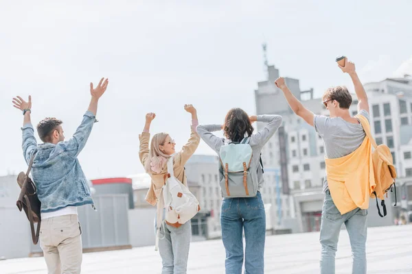 Back view of young stylish tourists gesturing having fun and walking in city — Stock Photo