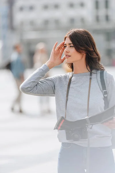 Thoughtful tourist with photo camera and map in city — Stock Photo