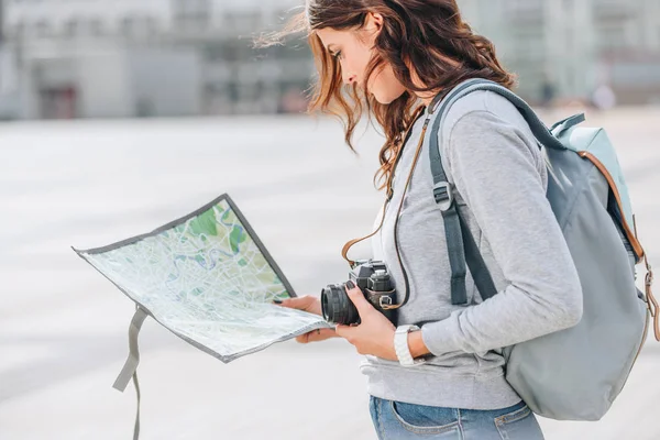 Female traveler with photo camera looking at map in city — Stock Photo