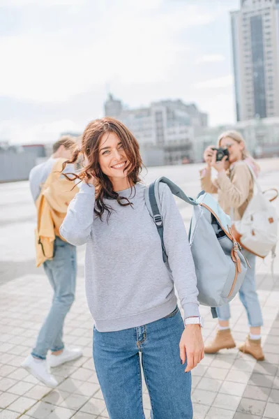 Fröhliche Brünette Mädchen zu Fuß mit Freunden in der Stadt — Stockfoto