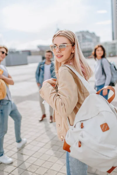 Young stylish girl walking in city with friends — Stock Photo