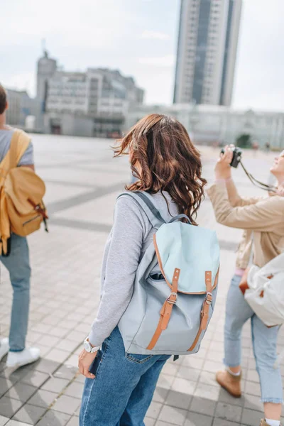 Visão traseira de turistas com mochilas e câmera fotográfica andando na cidade — Fotografia de Stock