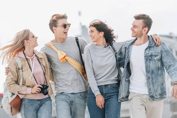 Young happy tourists hugging and walking in city together — Stock Photo