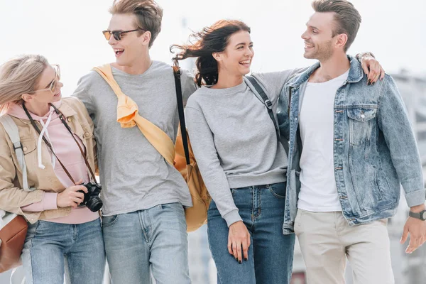 Young smiling travelers hugging and walking in city — Stock Photo