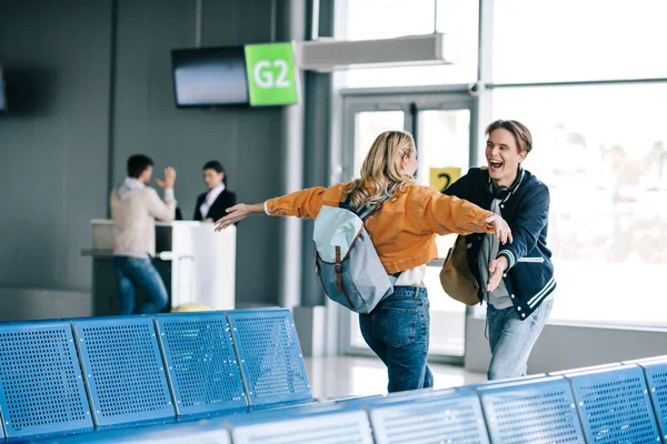 Happy young couple with backpacks hugging in airport terminal — Stock Photo