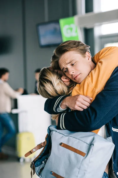 Vista de cerca de la joven pareja emocional abrazándose en la terminal del aeropuerto - foto de stock