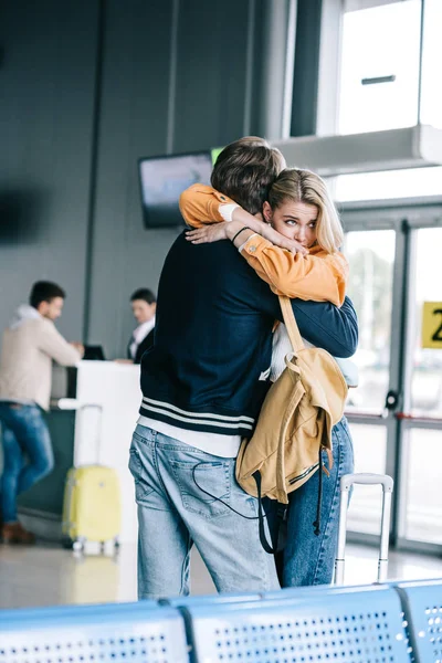 Emocional joven pareja abrazos en aeropuerto terminal - foto de stock