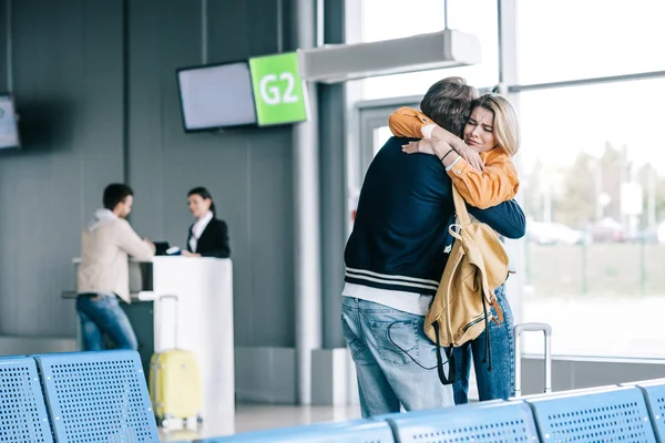 Emotional young couple hugging in airport — Stock Photo