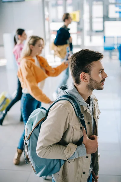 Высокий угол обзора молодых людей с багажом, смотрящих в терминале аэропорта — стоковое фото