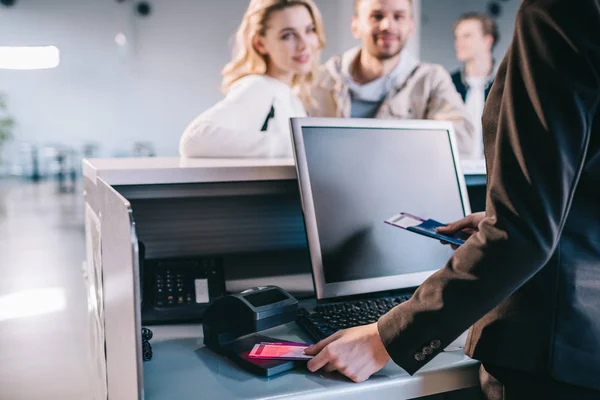 Colpo ritagliato del lavoratore dell'aeroporto che controlla i documenti al banco del check-in in aeroporto — Foto stock