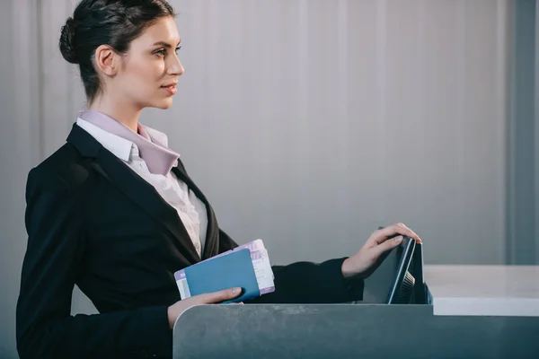 Side view of young female worker at check-in desk in airport — Stock Photo