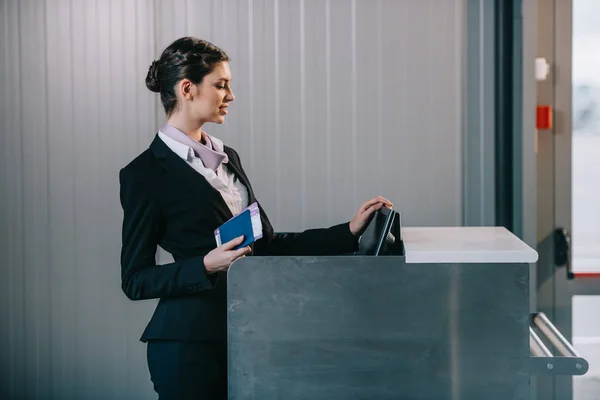 Beautiful young female worker at check-in desk in airport — Stock Photo