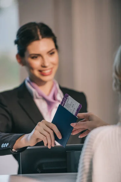 Trabalhador sorridente do aeroporto dando passaporte com cartão de embarque para jovens viajantes no balcão de check-in — Fotografia de Stock