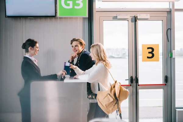 Вид на счастливую молодую пару у стойки регистрации в аэропорту — стоковое фото